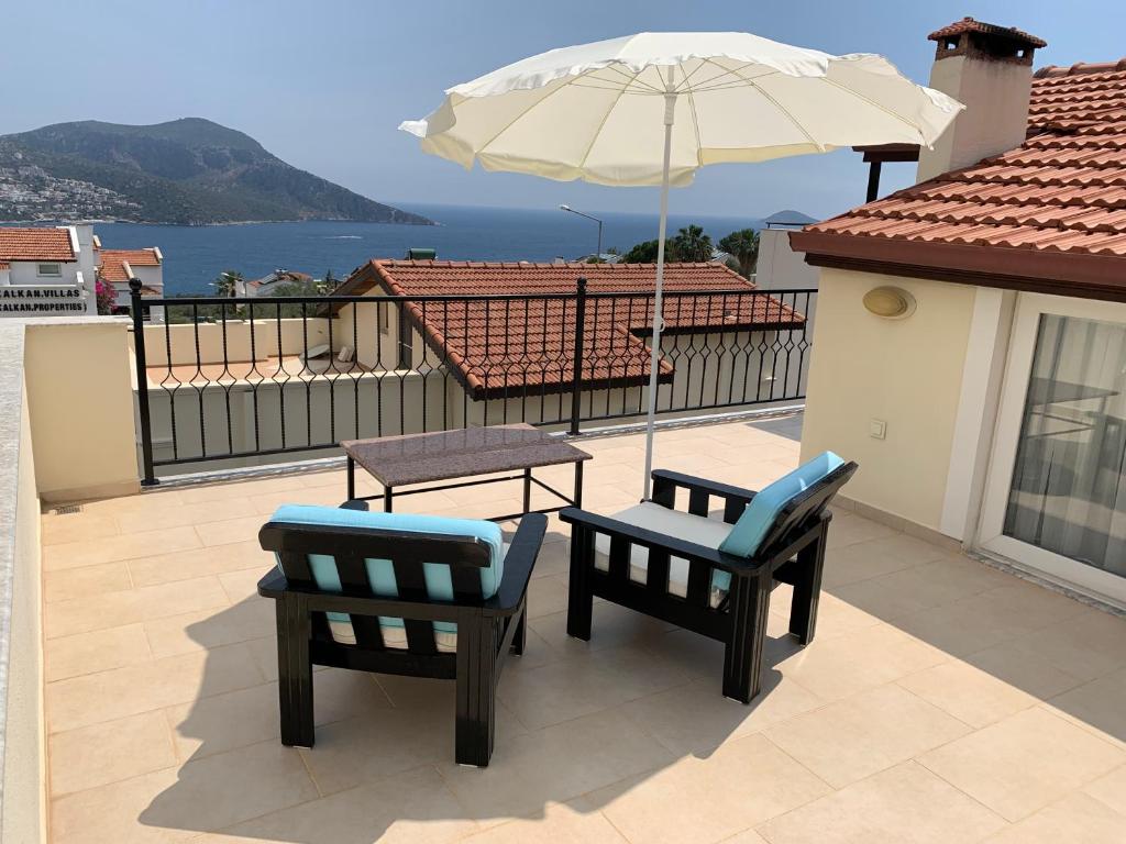 Un patio con dos sillas y una mesa y una sombrilla. en Kalkan Şener Apart, en Kas
