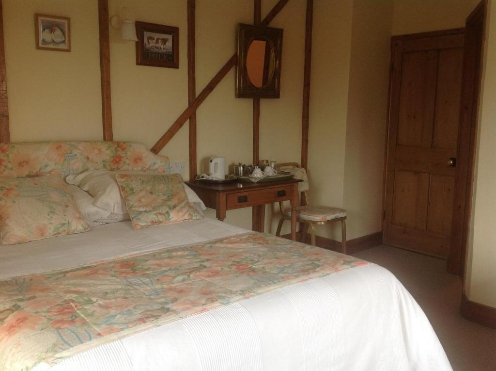 a bedroom with a bed and a table with a mirror at Barn Park Farm, Bed and Breakfast in Honiton