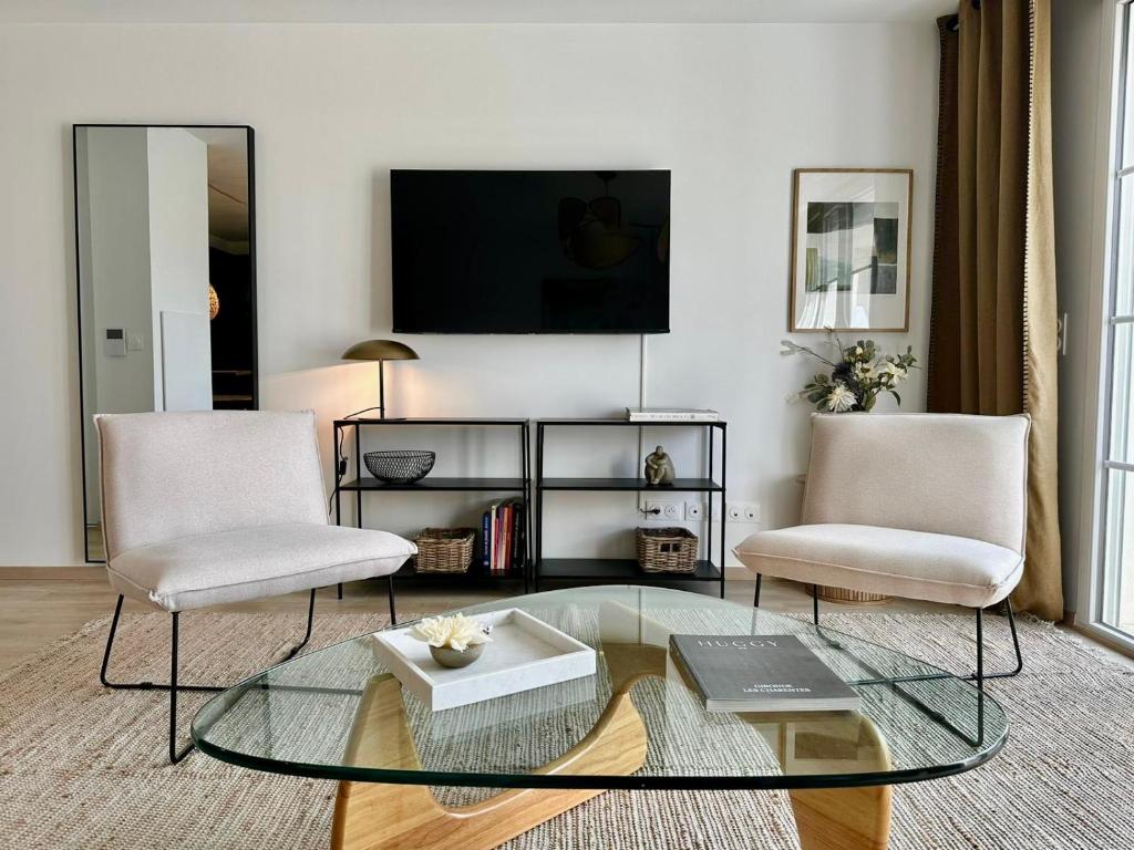 a living room with two chairs and a glass table at Charmant appartement T3 contemporain au bord de l'eau sur le Bassin Arcachon in Lanton