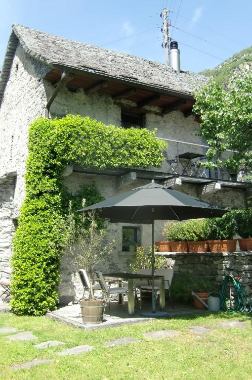 a table with an umbrella in front of a building at Fienile in Avegno
