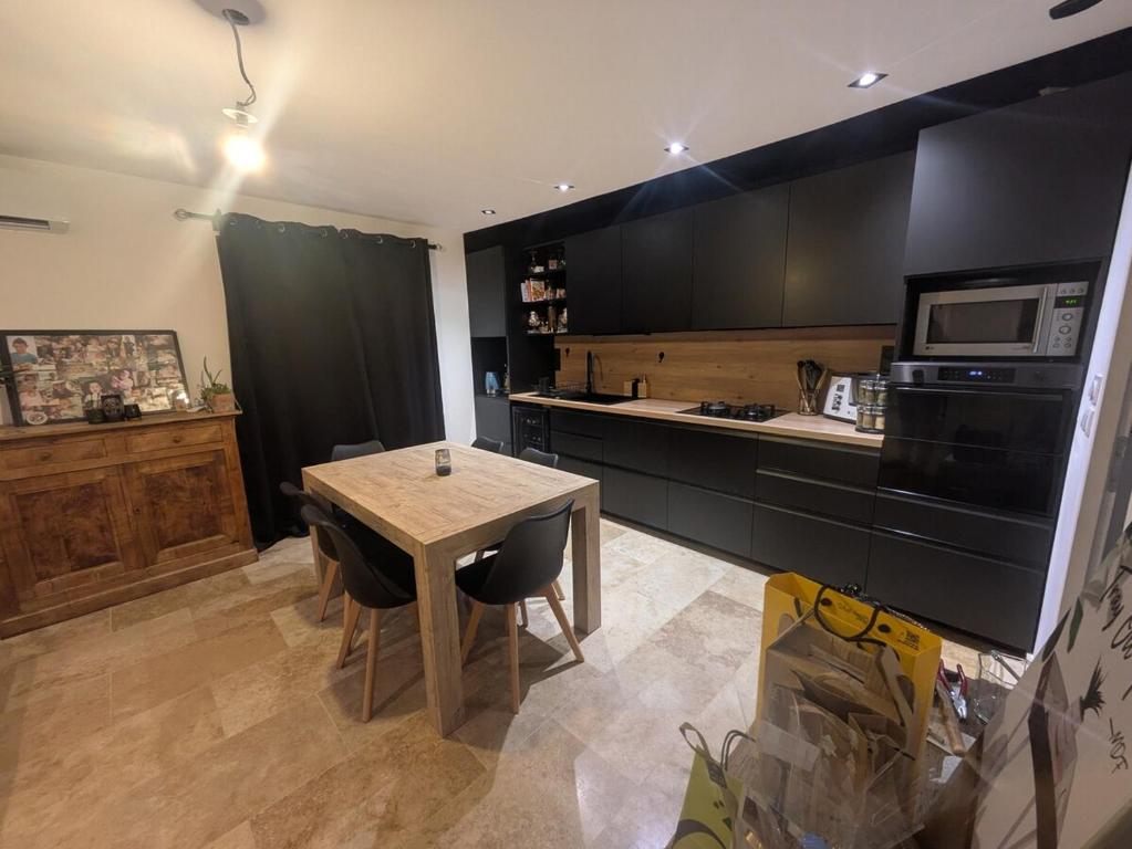 une cuisine avec une table avec des chaises et un micro-ondes dans l'établissement charmante petite maison - piscine hors sol - proche Avignon, à Avignon