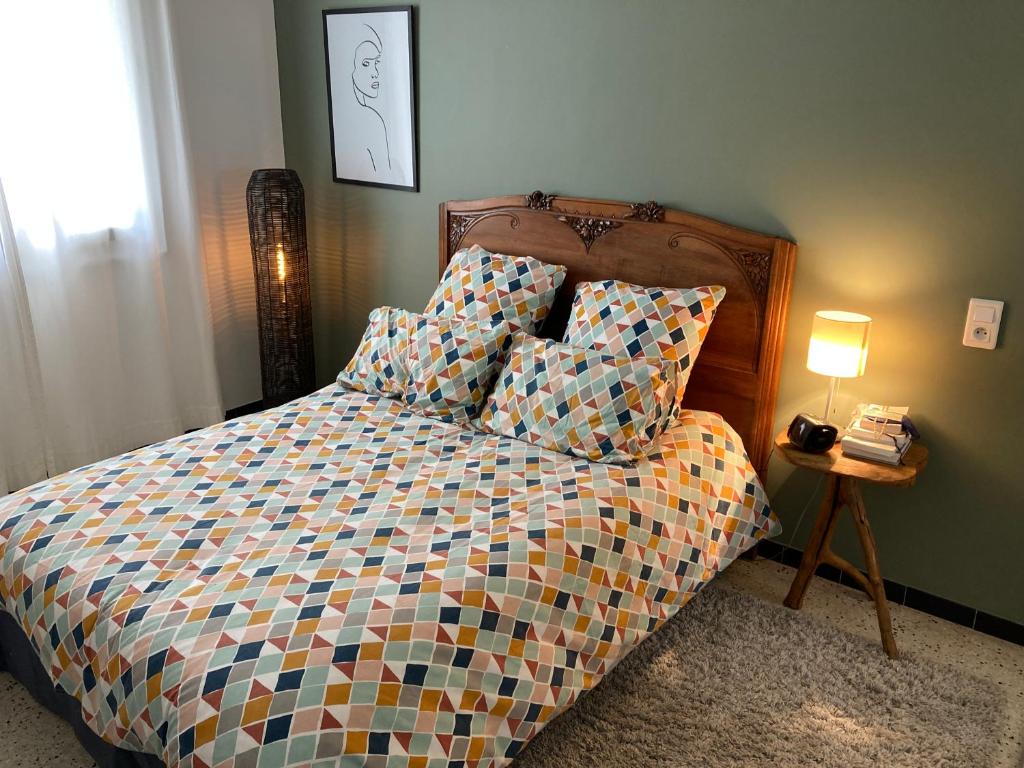 - un lit avec une couette colorée et une table de chevet dans l'établissement Location appartement de vacances Ajaccio, à Ajaccio