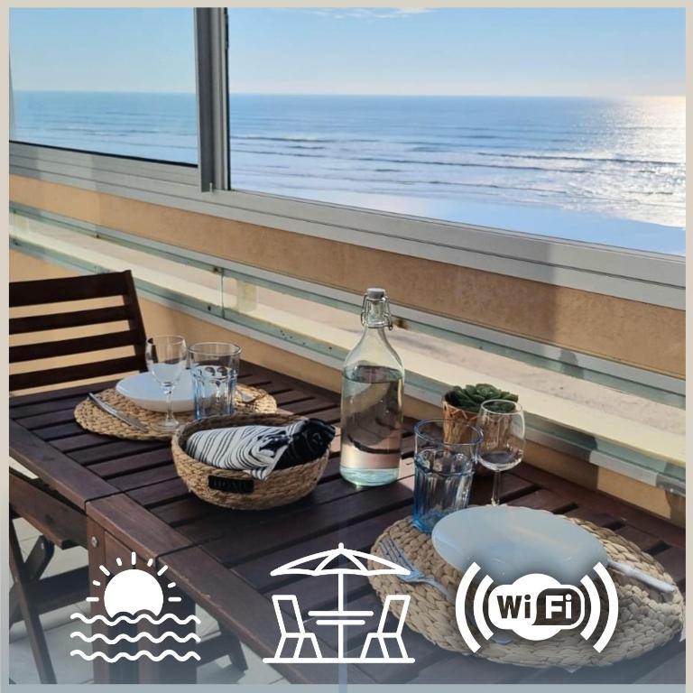 - une table avec des assiettes et des verres sur une table avec vue sur l'océan dans l'établissement Au bruit des vagues, vue mer, à Saint-Hilaire-de-Riez