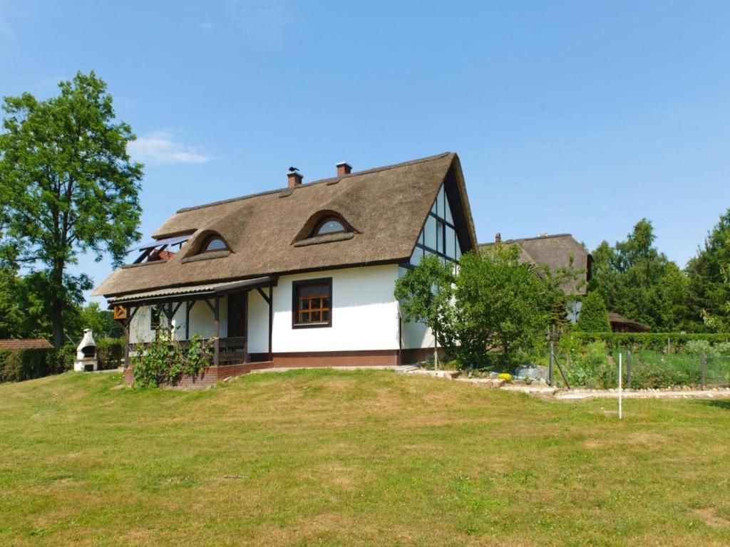 a white house on top of a grassy hill at holiday home with thatched roof, Rekowo in Rekowo