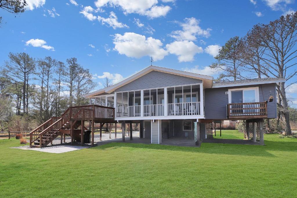 a large house with two decks on a lawn at Our Happy Place - Pet friendly & waterfront! in Deep Hole