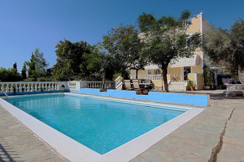 una piscina de agua azul frente a una casa en Villa Emily en Lagonissi