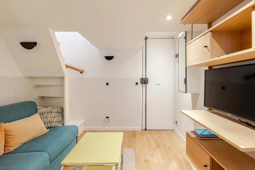 un salon avec un canapé bleu et une télévision dans l'établissement Cosy Duplex in Central Paris, à Paris
