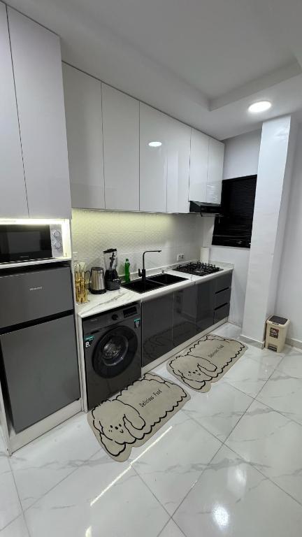 una cucina con mobili bianchi, fornelli e lavastoviglie di Triangle a Lekki