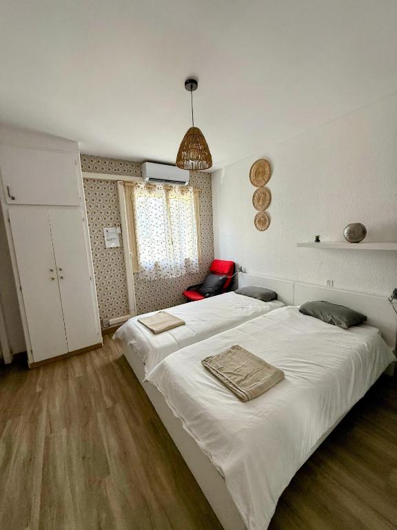 une chambre avec un grand lit blanc et une chaise rouge dans l'établissement Centre ville d'Amelie les bains, à Amélie-les-Bains-Palalda