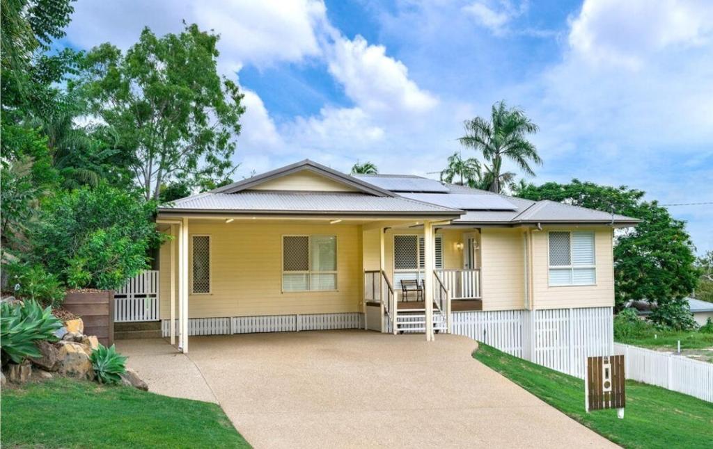 una casa amarilla con una valla blanca en Lamington Cottage, en The Range