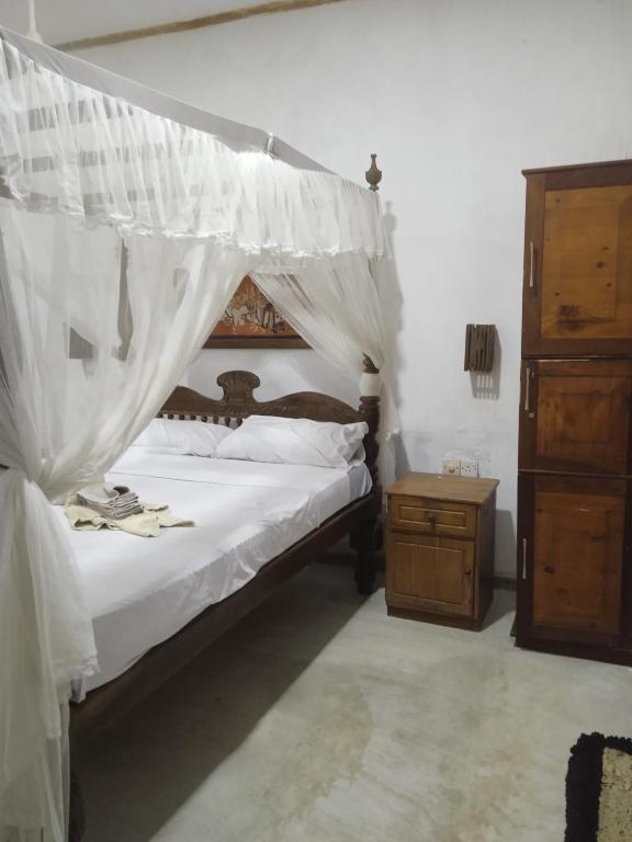 a bedroom with a canopy bed and a wooden dresser at Chapel Home Stay in Ahungalla