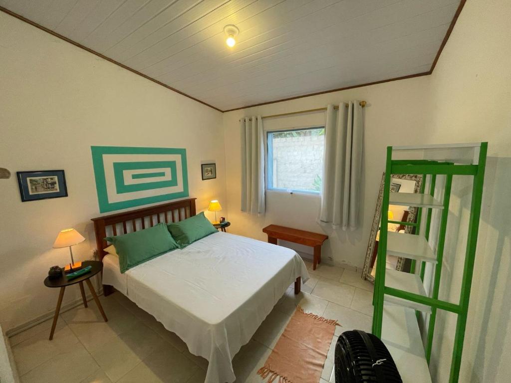 a bedroom with a bed and a green ladder at Casa caiçara Paraty in Paraty