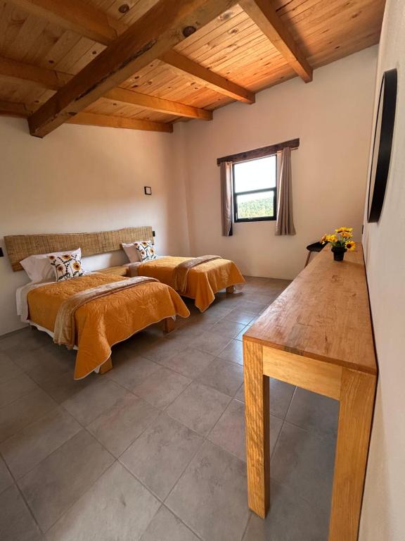 two beds in a room with wooden ceilings at Hotel Tlalcosahua, hotel de Montaña, Tapalpa in Tapalpa