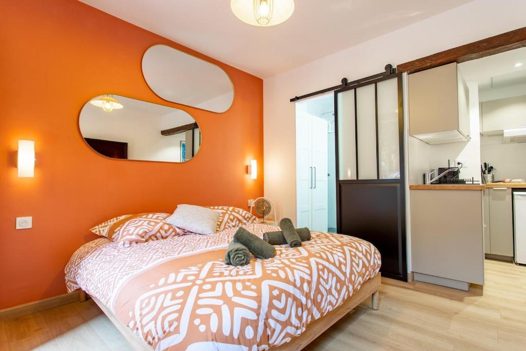 - une chambre avec un mur orange, un lit et un miroir dans l'établissement L'Escapade Hyper-Centre St Aubin, à Toulouse