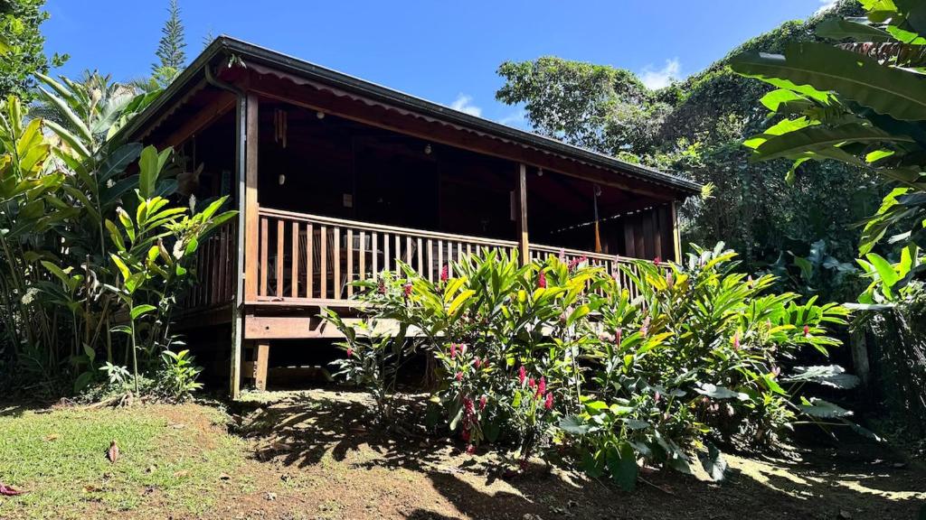 una casa con portico in mezzo a un giardino di Bungalow créole en pleine nature a Petit-Bourg