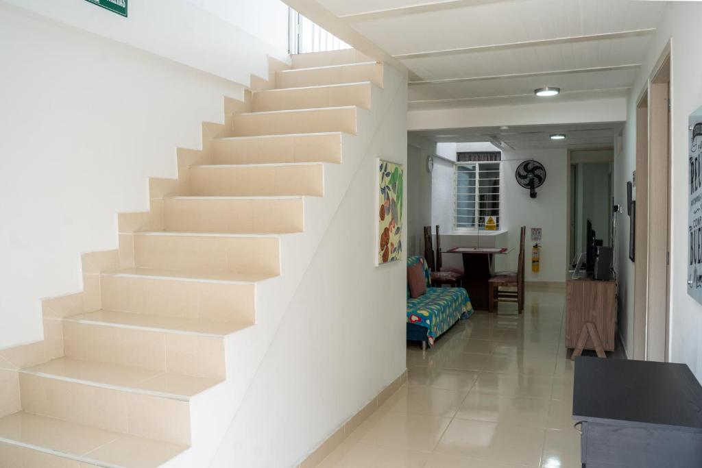 a staircase in a living room with white walls at ALQUILO''APARTAMENTO COMPLETO con ZONA PRIVADA SOCIAL BARBECUE BBQ'' para FAMILIAS-3 HABITACION-2 duchas in Cali