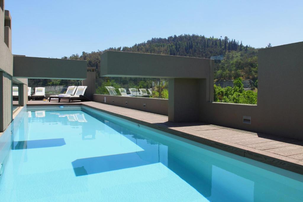 a swimming pool with a view of a house at Hotel Los Españoles Plus in Santiago