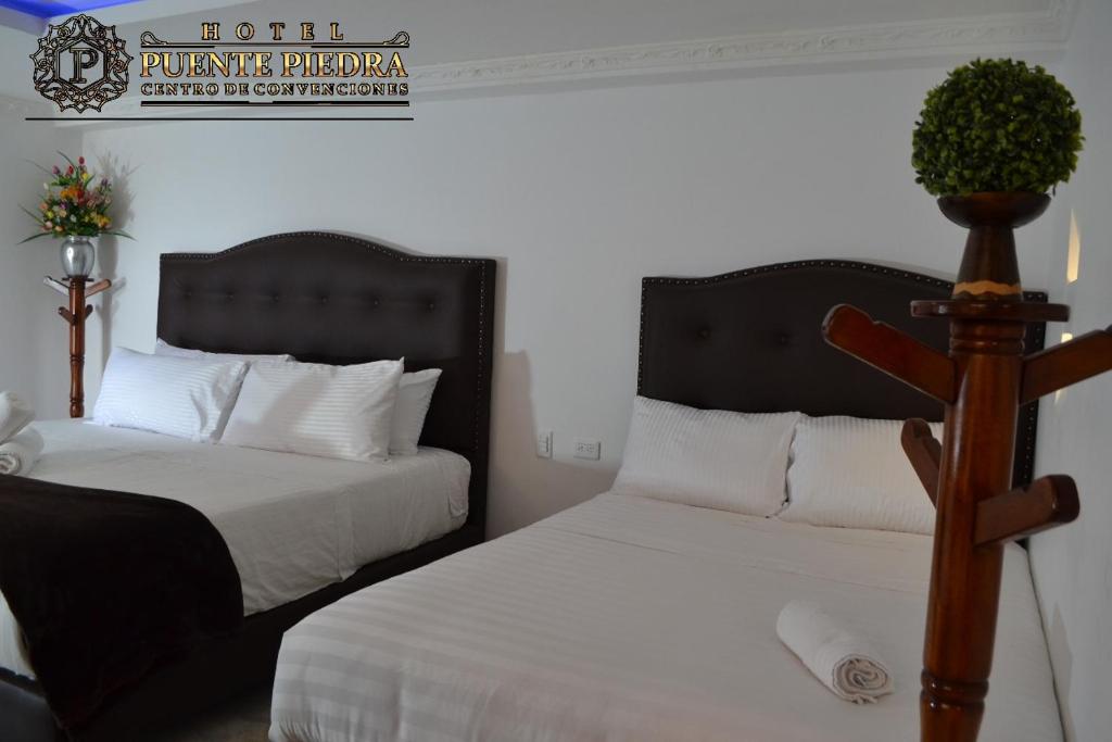 a bedroom with two beds and a plant on a pole at Hotel PUENTE PIEDRA PARK in Villa de Leyva