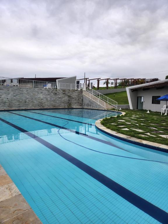 a large swimming pool with blue water at Casa Aconchegante em Condomínio Country in Conde