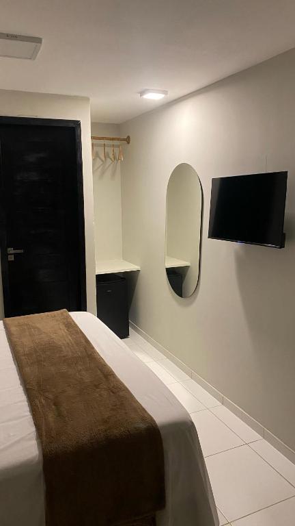 a bedroom with a bed and a tv on the wall at Aloha Noronha Suites in Fernando de Noronha