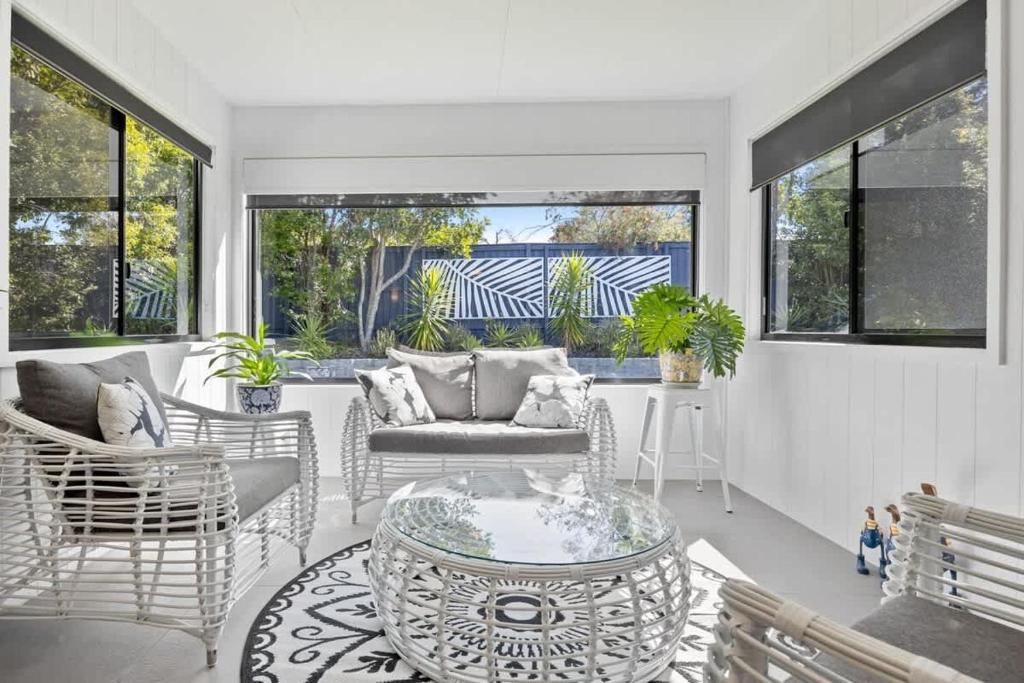- un salon avec des chaises en osier et une table dans l'établissement Waves Retreat - Coastal Style Home near Warana Beach, à Parrearra
