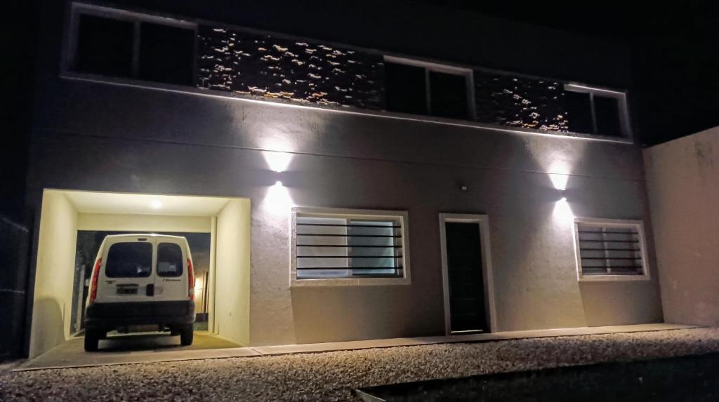 Una furgoneta blanca estacionada al lado de una casa por la noche en El Buen Vivir, en Mar del Plata