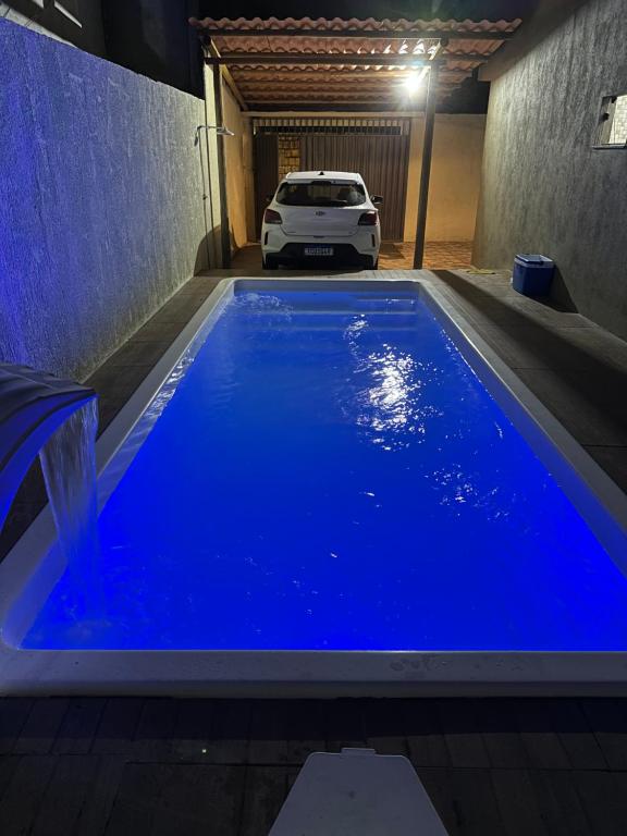 a pool of blue water in a garage with a car at Casa alegria 15 min do toa toa in Porto Seguro