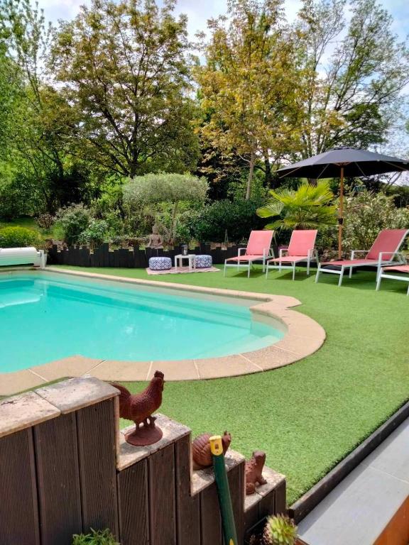 - une piscine avec de l'herbe verte à côté d'une cour dans l'établissement Gîte Malabeille, à Madaillan