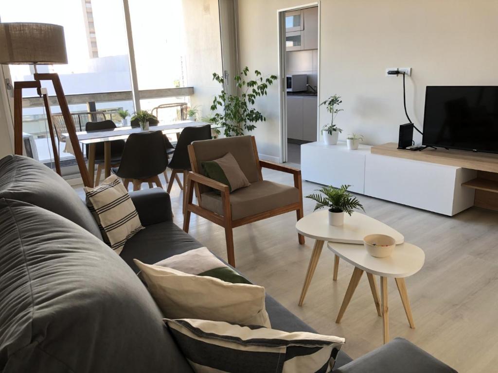a living room with a couch and a tv at Departamento JACARANDA con cochera in Bahía Blanca