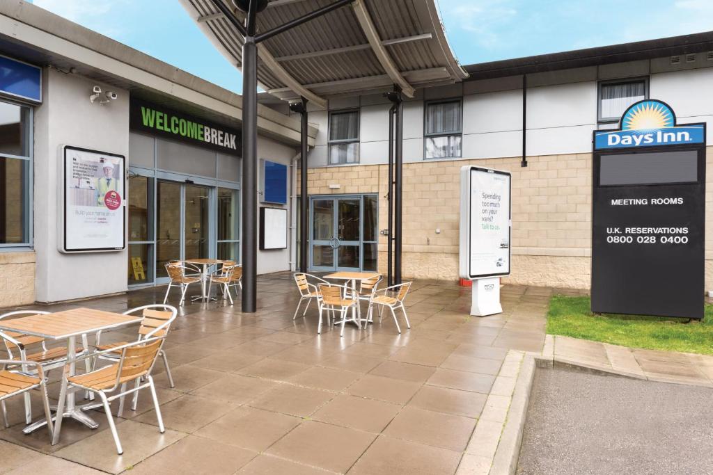 a patio with tables and chairs in front of a building at Days Inn by Wyndham Donington in Castle Donington