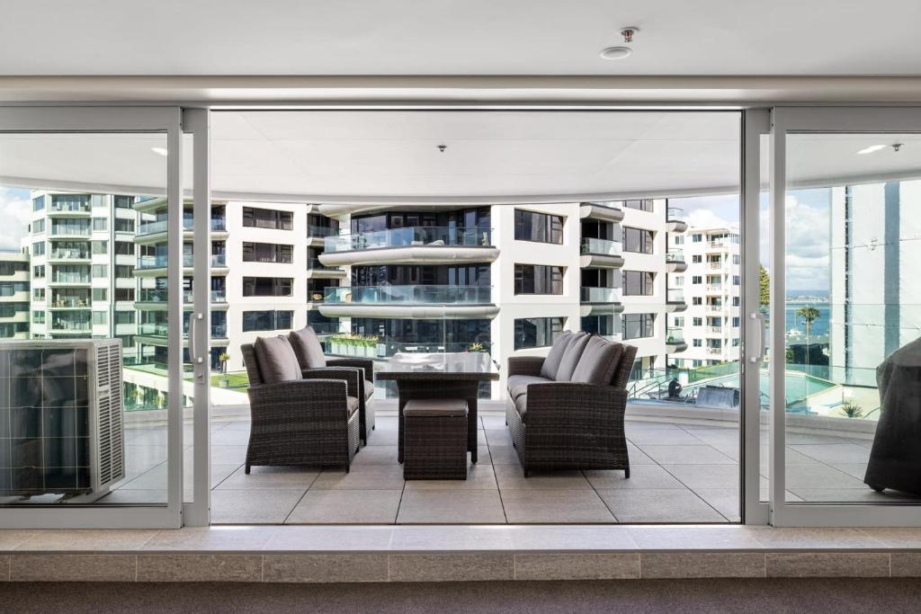 a patio with chairs and a table on a balcony at A Strand of Paradise, Oceanside Views & Pool in Mount Maunganui