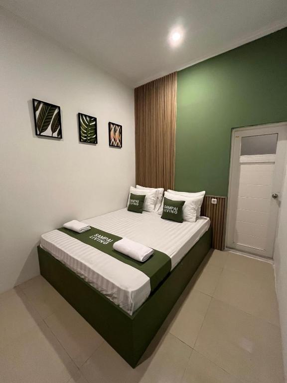 a bedroom with a bed with green and white walls at Sampai Town Hotel in Adi Sutjipto