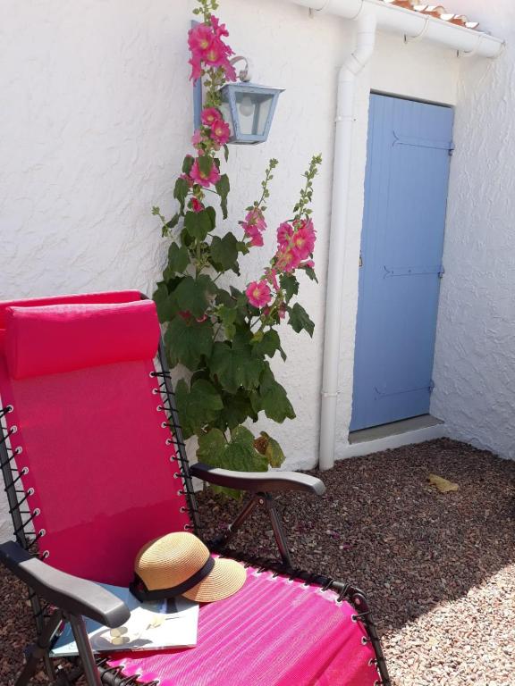 une chaise rouge avec un chapeau assis à côté d'une porte dans l'établissement Les volets bleus, à Saint-Gilles-Croix-de-Vie