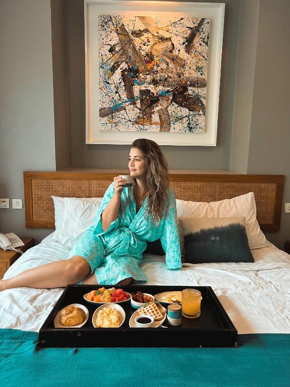 a woman sitting on a bed with a tray of food at Ecozy Dijiwa Canggu in Canggu