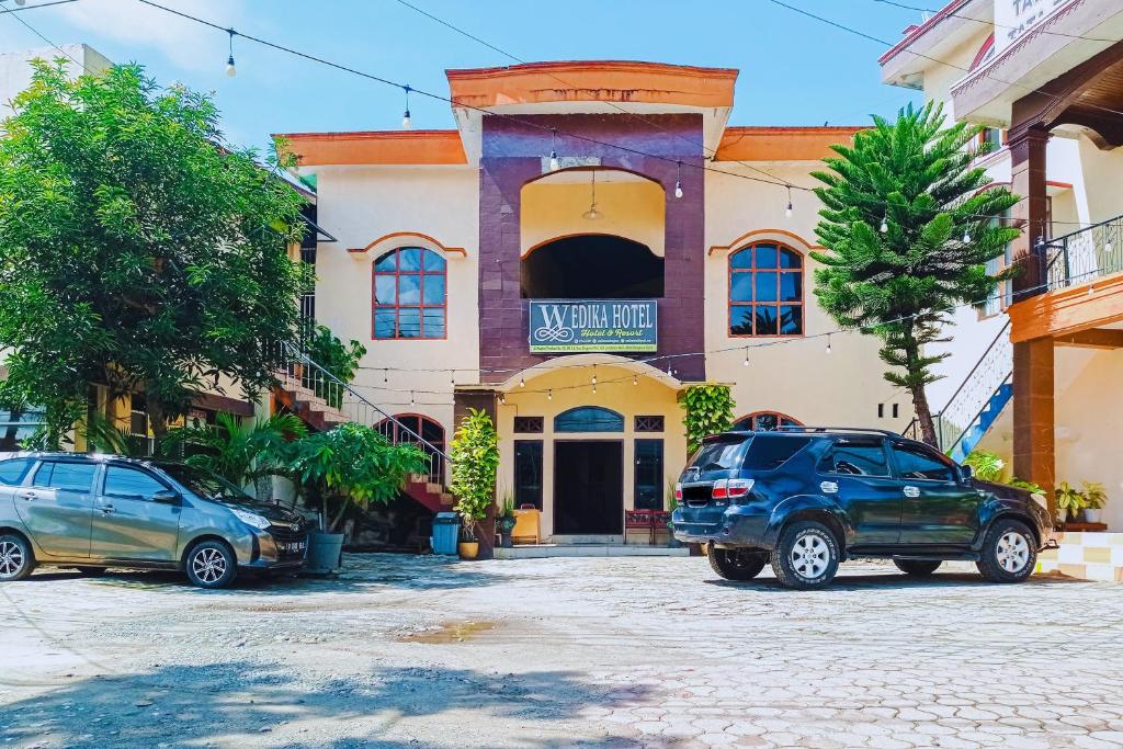 two cars parked in front of a building at Urbanview at Wedika Hotel Bengkulu in Bengkulu