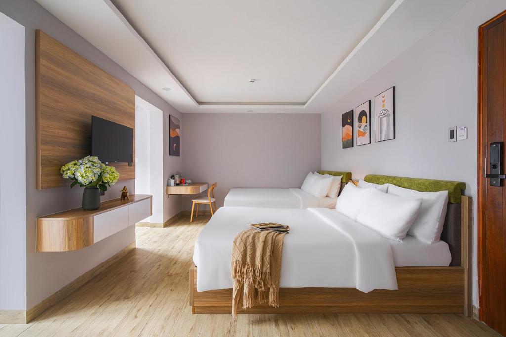 a bedroom with a large white bed and a table at Nature Hotel - Win Happy in Da Lat