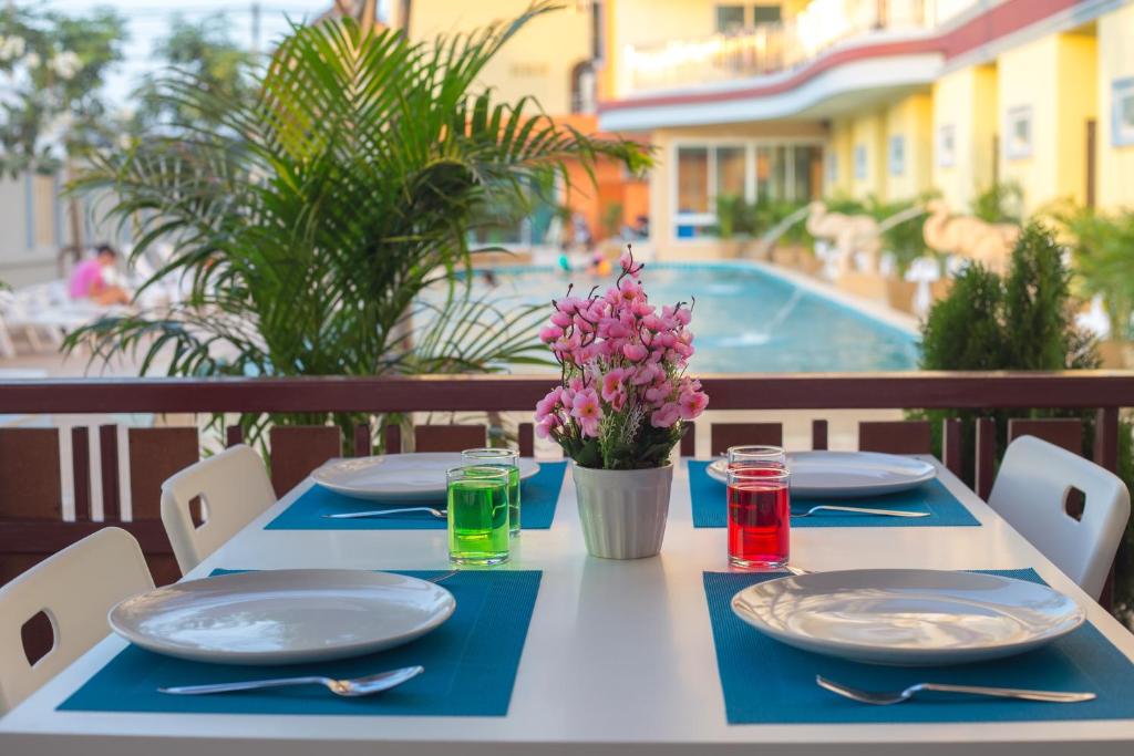 stół z talerzami i naczyniami na stole z basenem w obiekcie Smile Residence w mieście Rawai Beach