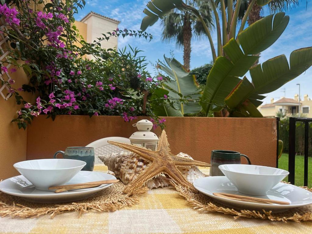 ein Tisch mit zwei weißen Schüsseln und einem Seestern darauf in der Unterkunft Indalia Natura, apartamento nudista en Vera playa in Vera