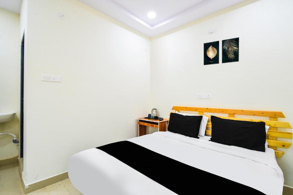 a white room with a bed with black pillows at Super Collection O Adibatla Hyderabad in Ibrāhīmpatan