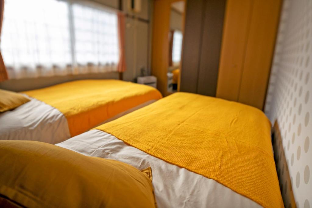 網走市にあるMove8の黄色い毛布が備わる客室内のベッド2台