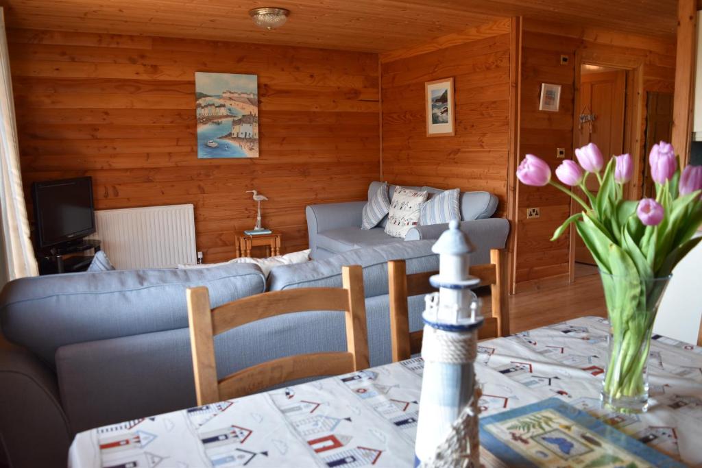 a living room with a couch and a table with flowers at East Crinnis Log Cabin in Par