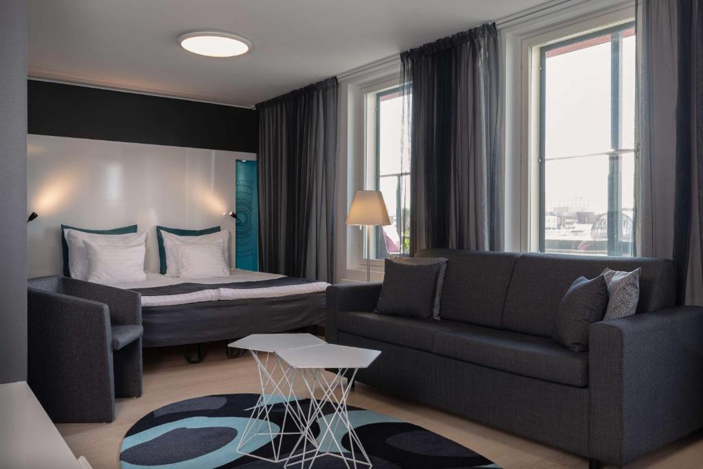 a living room with a couch and a bed at Scandic Tampere Station in Tampere