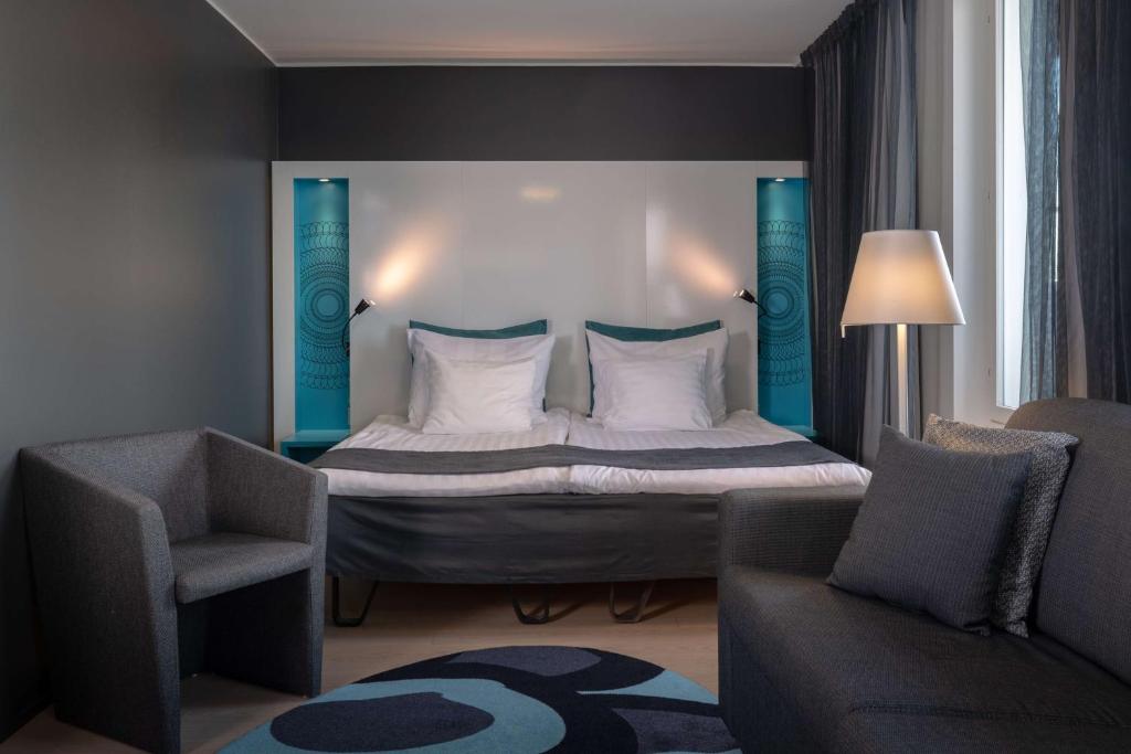 a bedroom with a bed and a couch and a chair at Scandic Tampere Station in Tampere