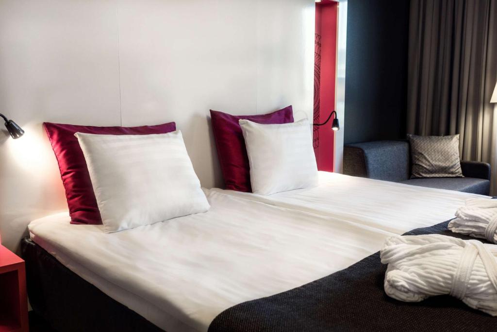 a hotel room with a large bed with red and white pillows at Scandic Tampere Station in Tampere