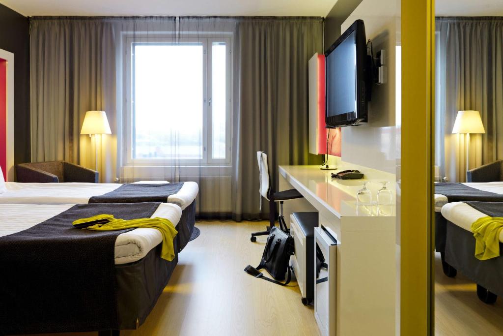a hotel room with two beds and a flat screen tv at Scandic Tampere Station in Tampere