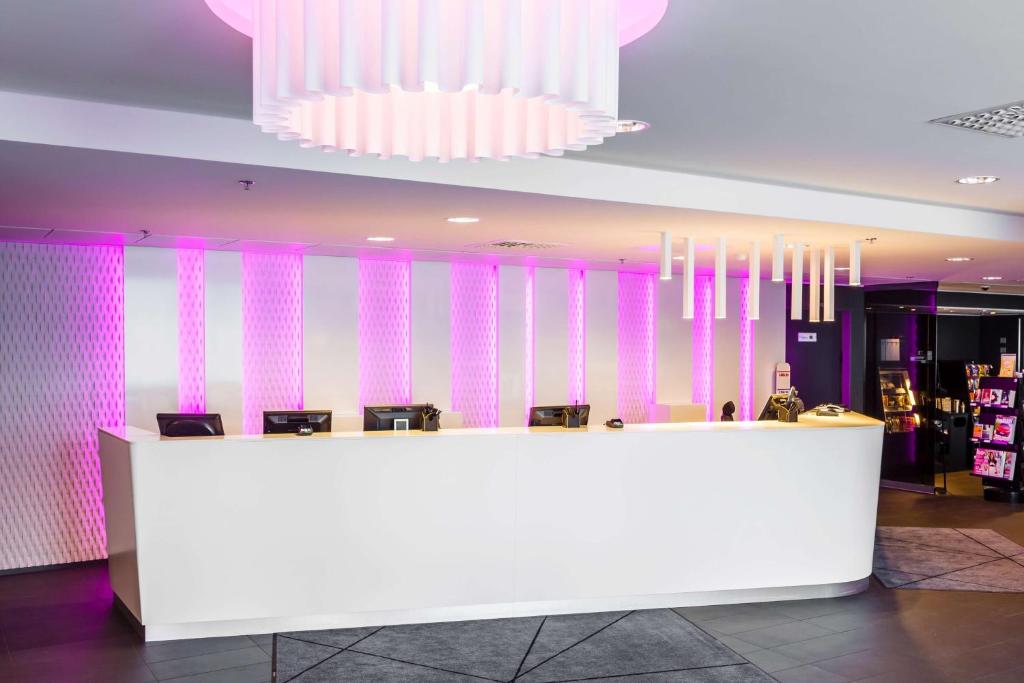 a lobby with a white counter and pink walls at Scandic Tampere Station in Tampere