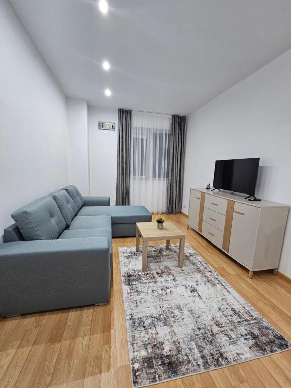 ein Wohnzimmer mit einem blauen Sofa und einem Fernseher in der Unterkunft Rin Elegance Apartament in Bukarest