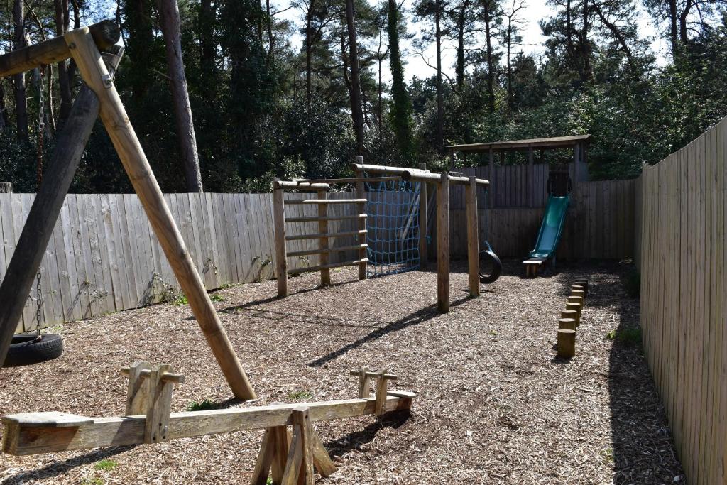 a playground with a swing set and a wooden fence at East Crinnis Log Cabin in Par