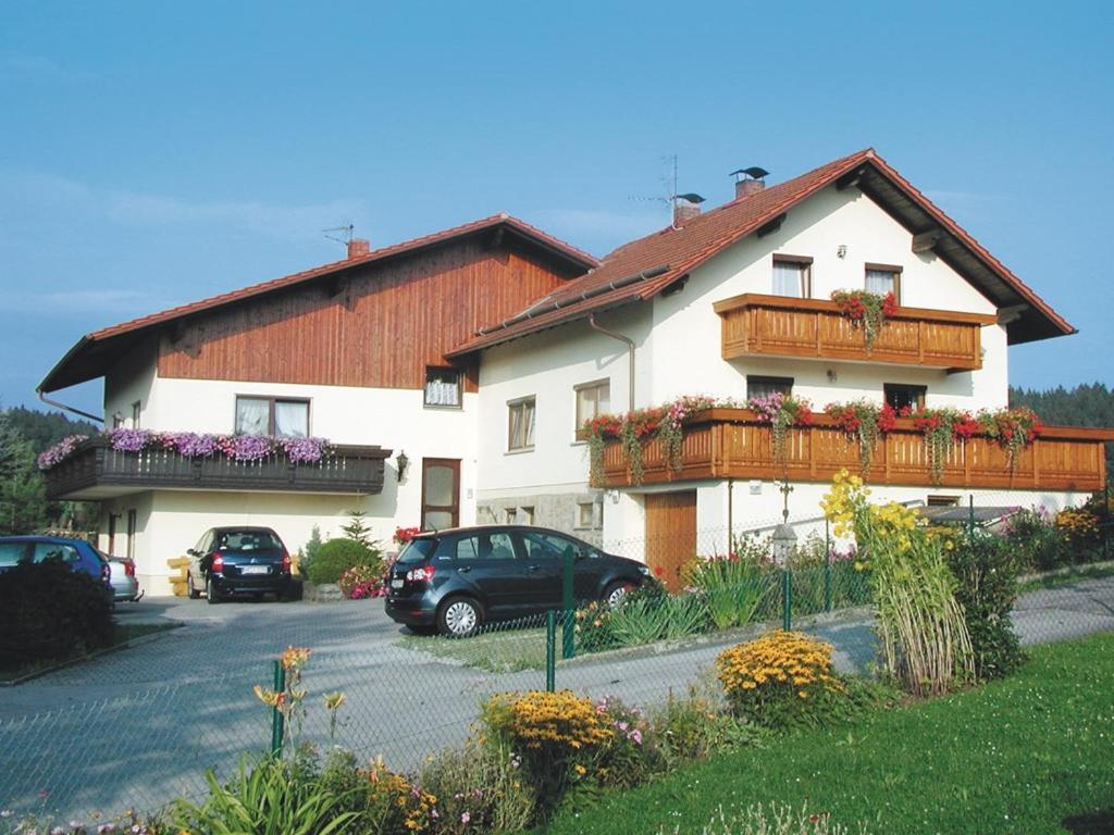 ein großes Haus mit Balkonen und Autos auf einem Parkplatz in der Unterkunft Ferienwohnung Rank in Blaibach