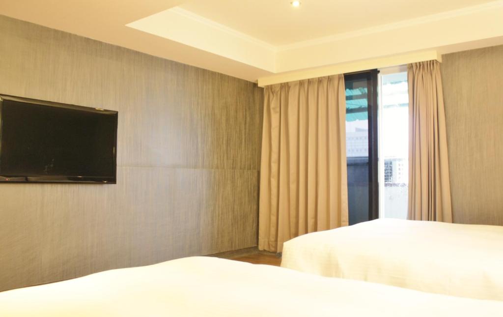 a hotel room with two beds and a flat screen tv at LIHO Hotel Tainan in Tainan